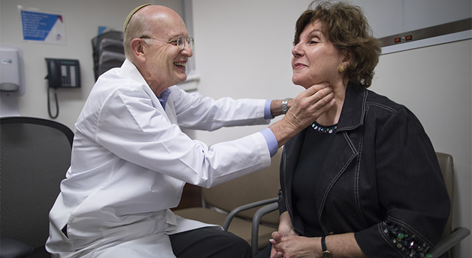 Dr. Terry Davies examines a patient’s thyroid