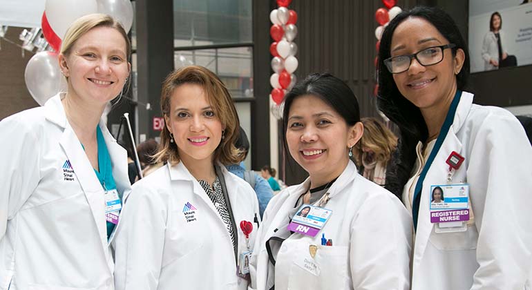 Four female nurses posing at an event. Each are in a lab coat