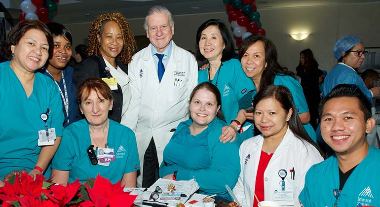 Group of female and male nurses in scrubs posing with male physician