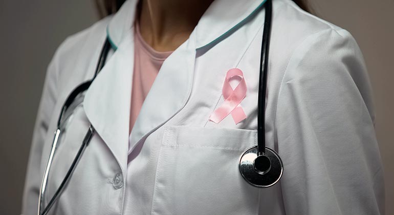 person in a white coat with a pink riibbon on for breast cancer support