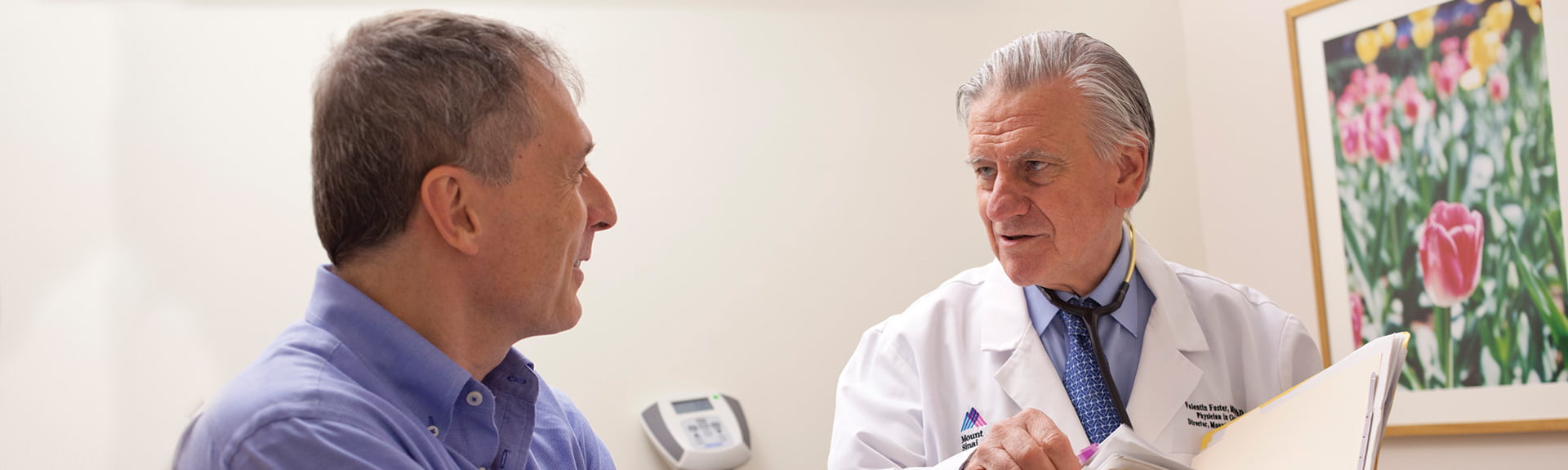 Male physician with a male patient looking over patients records and talking