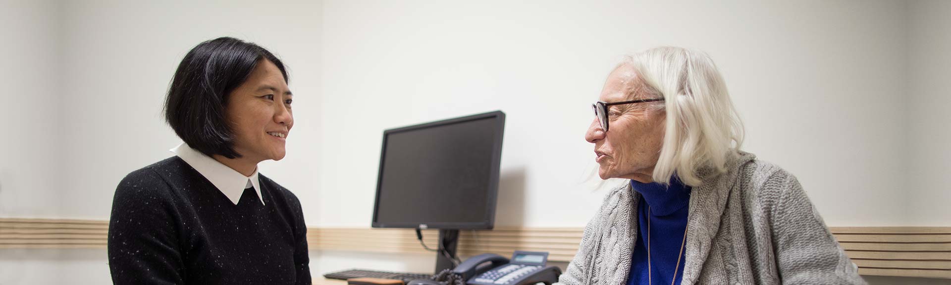 Female geriatric patient talking to medical professional in examination room