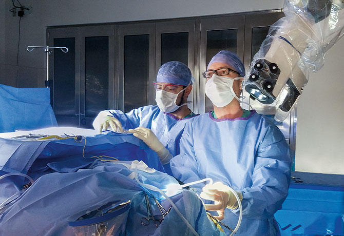 A photo of George Wanna, MD, using exoscopic technology in the operating room.