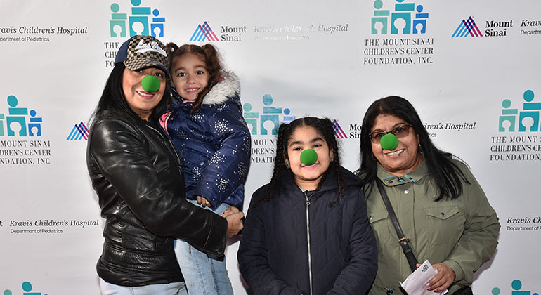 Two women and two girls wearing green clown noses