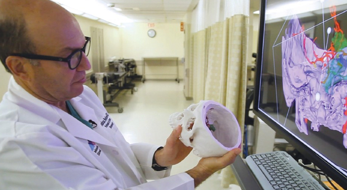 image of Dr. Bederson reviewing 3D printed brain, comparing it to scan on computer screen
