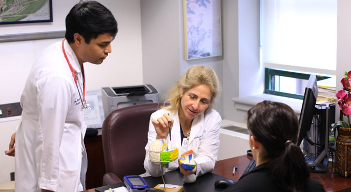 image of Dr. Germano reviewing brain model with another physician and patient in office setting