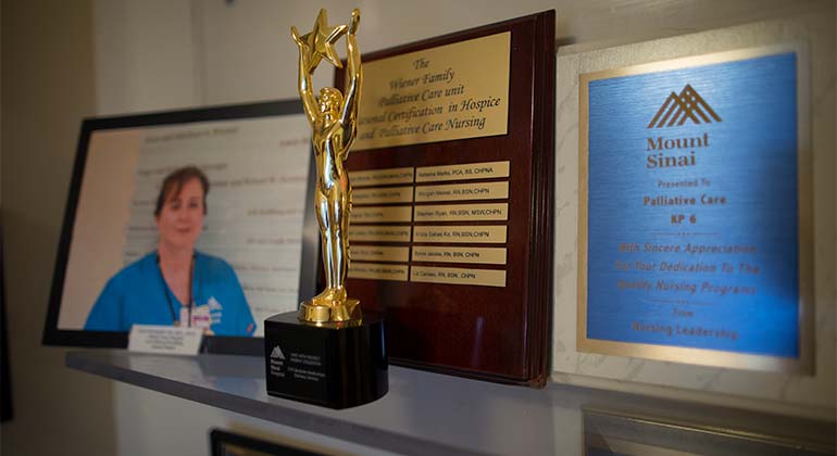 Photo of the palliative care department achievements: a trophy with two plaques and a photo of a nurse.