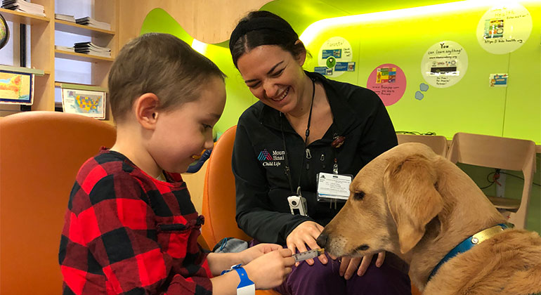 Image of little boy and nurse with dog