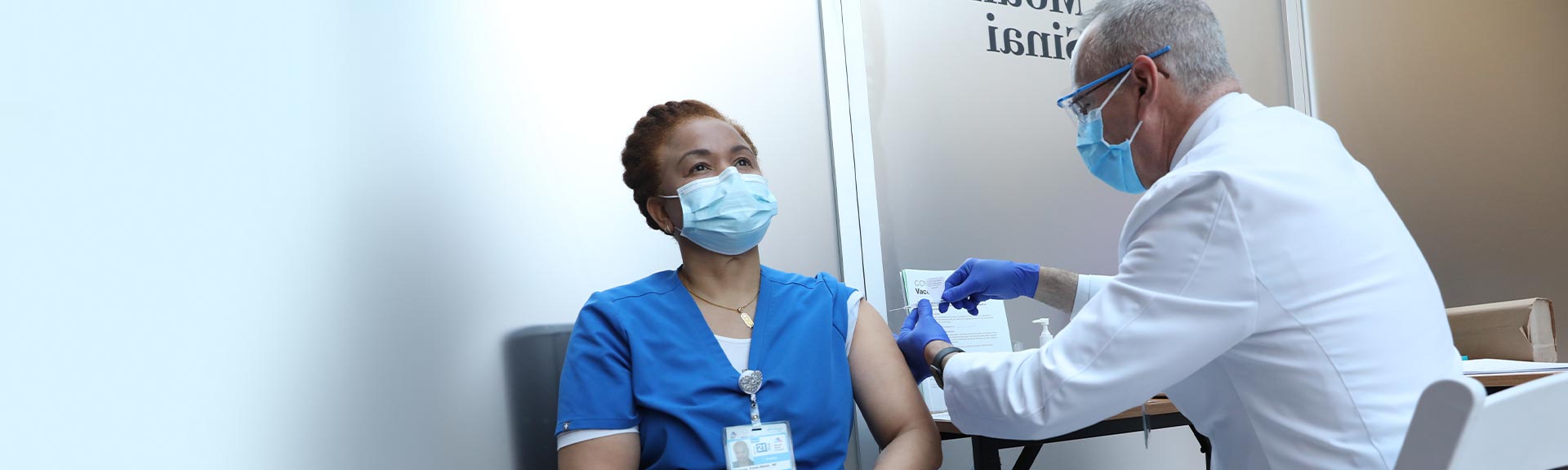 Image of doctor putting vaccine on nurse