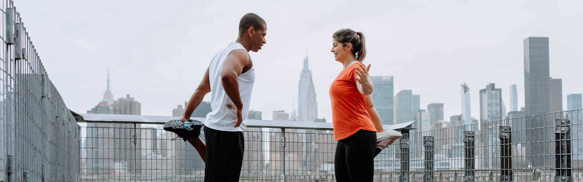 A man and women standing on one leg stretching on a balcony