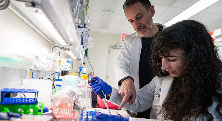 A male professor helping a female student in a lab