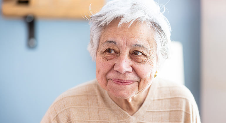A headshot of an older female patient in an exam room.