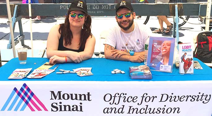 A man and woman sit behind a booth with a sign that says "Mount Sinai Office for Diversity and Inclusion"