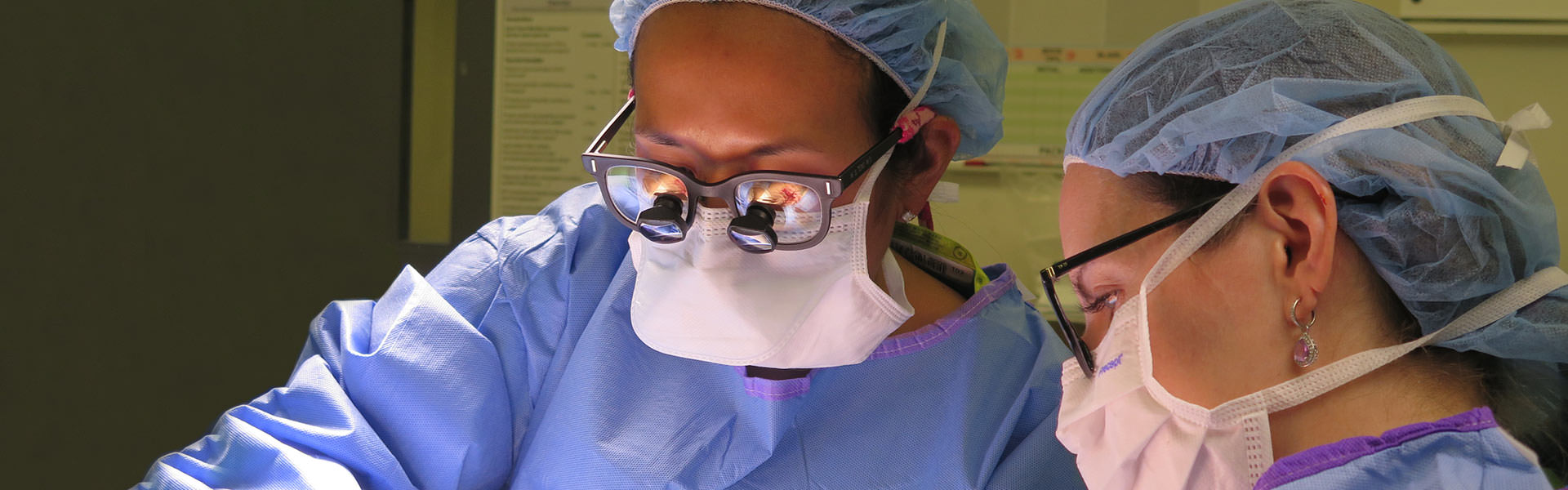 Two surgeons with surgical gear looking down at patient 