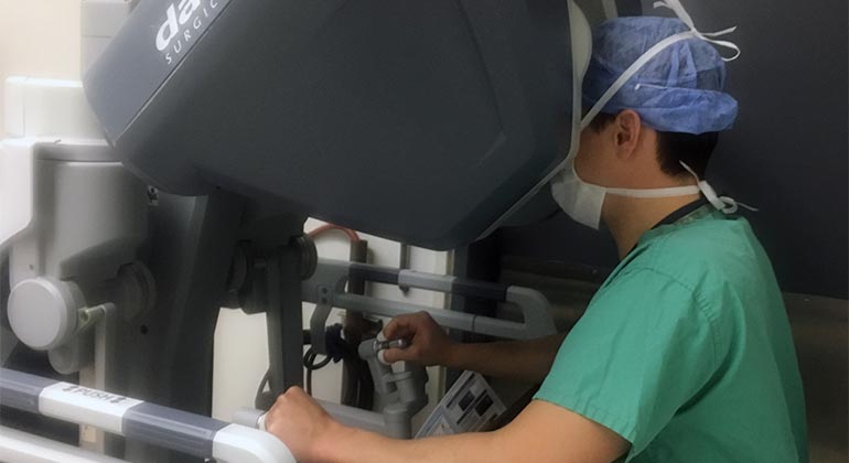 Surgeon looking through lens of the robotic machine
