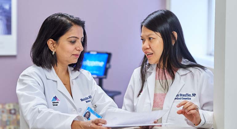 Two female members of medical staff speaking and looking at paper 