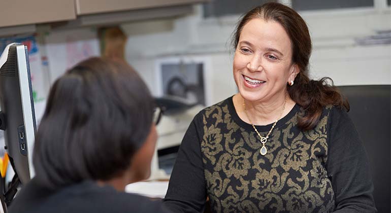 Female patient speaking with medical staff member, sitting at desk