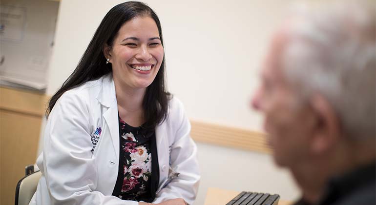 Seated female doctor smiling at male geriatric patient