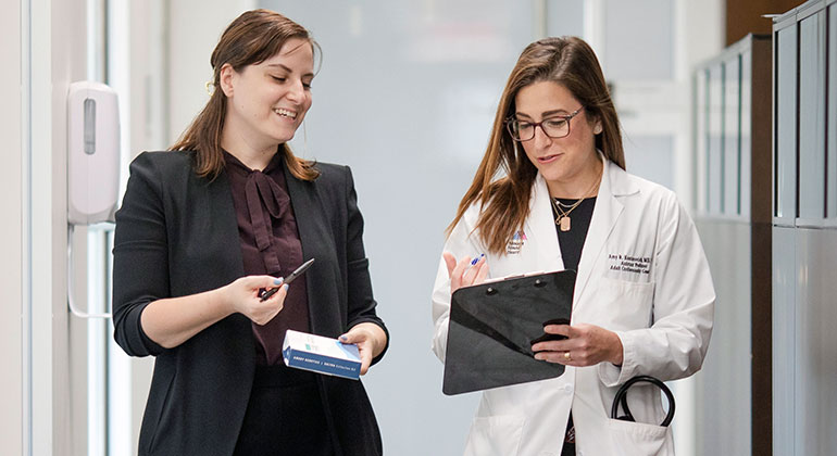 doctor with clipboard with staffwalking down hallway with 