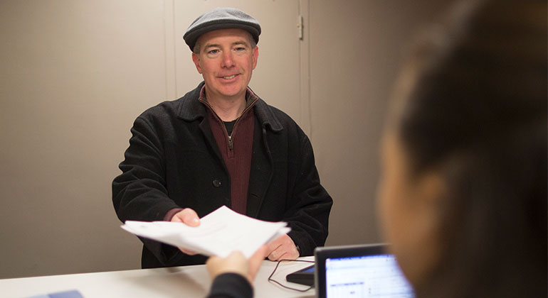 patient handing a receptionist forms