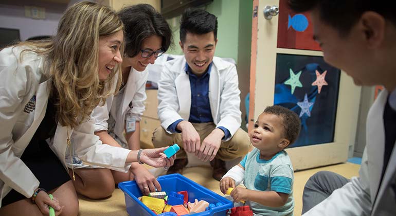 Image of doctors playing with toddler 