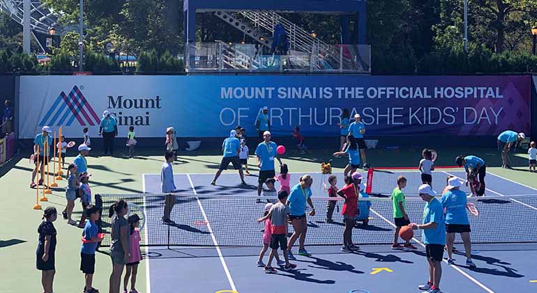 Image of kids and trainers in tennis clinic