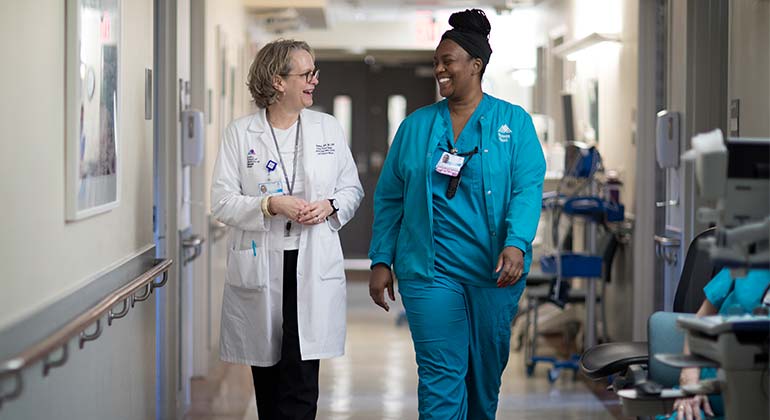 Two smiling nurses walking down the hospital hallway