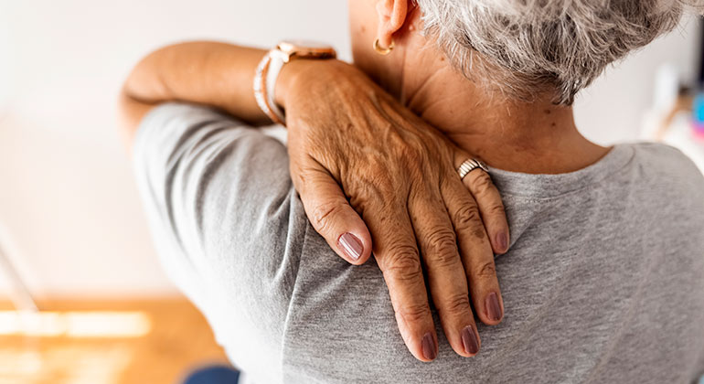 person touching the back of their shoulder