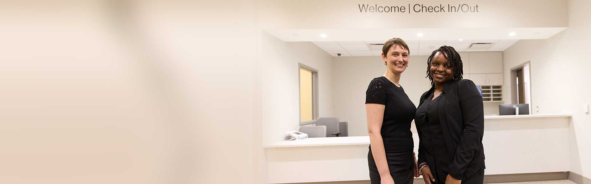 two individuals standing in the check in/out area of a hospital department