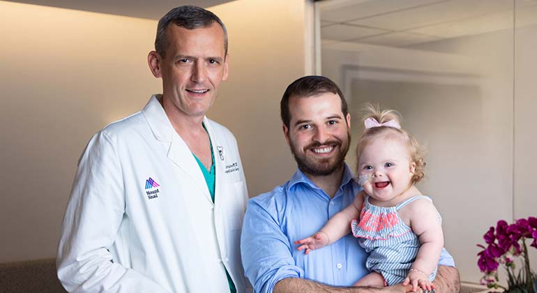 Image of father holding baby girl next to male doctor