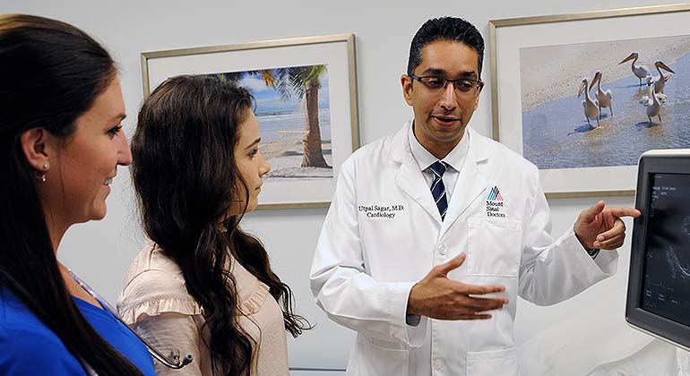 Doctor showing scan on screen to patient and nurse