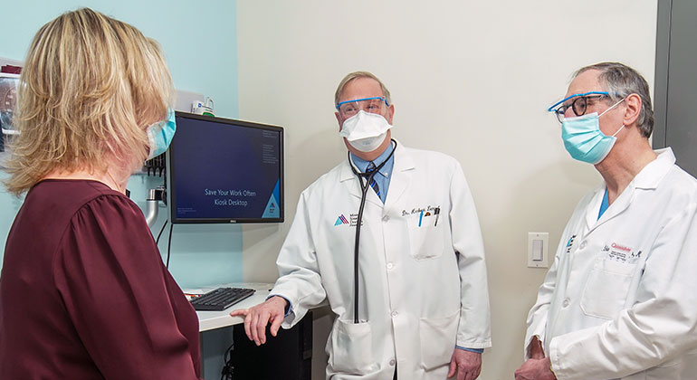 Two male doctors speaking with female patient