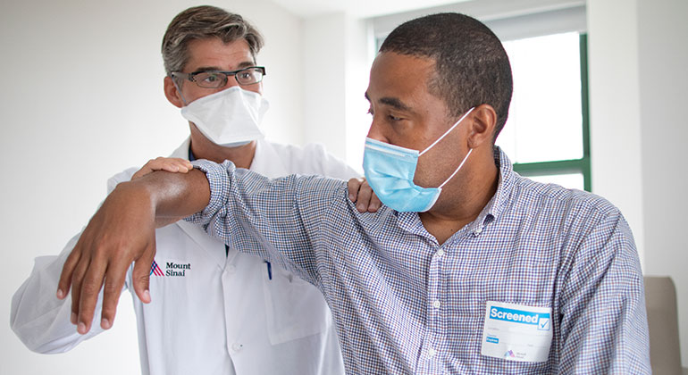 Male patient having arm examined by orthopedist