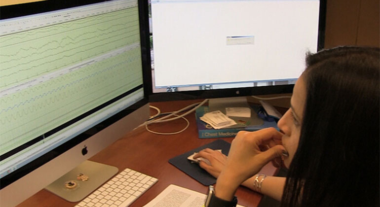 Sleep technician reviewing sleep study test results on computer at sleep services department 