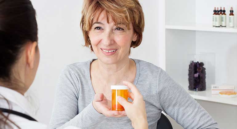 Pharmacists hands patient a medicine bottle