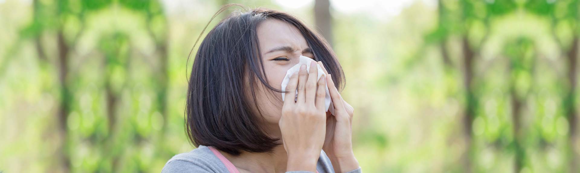 Woman sneezing into tissue