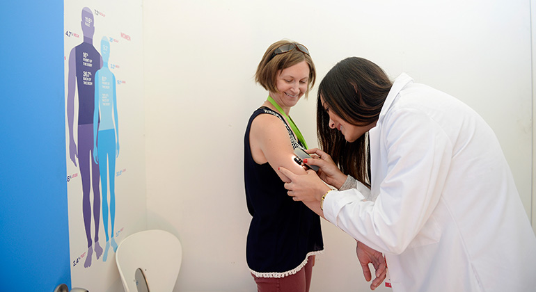 Dermatologist Noelani Gonazlez, MD, performing a skin cancer screening on an attendee