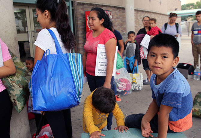 A photo showing families in Texas waiting to board a bus that will take them to their immigration hearings.