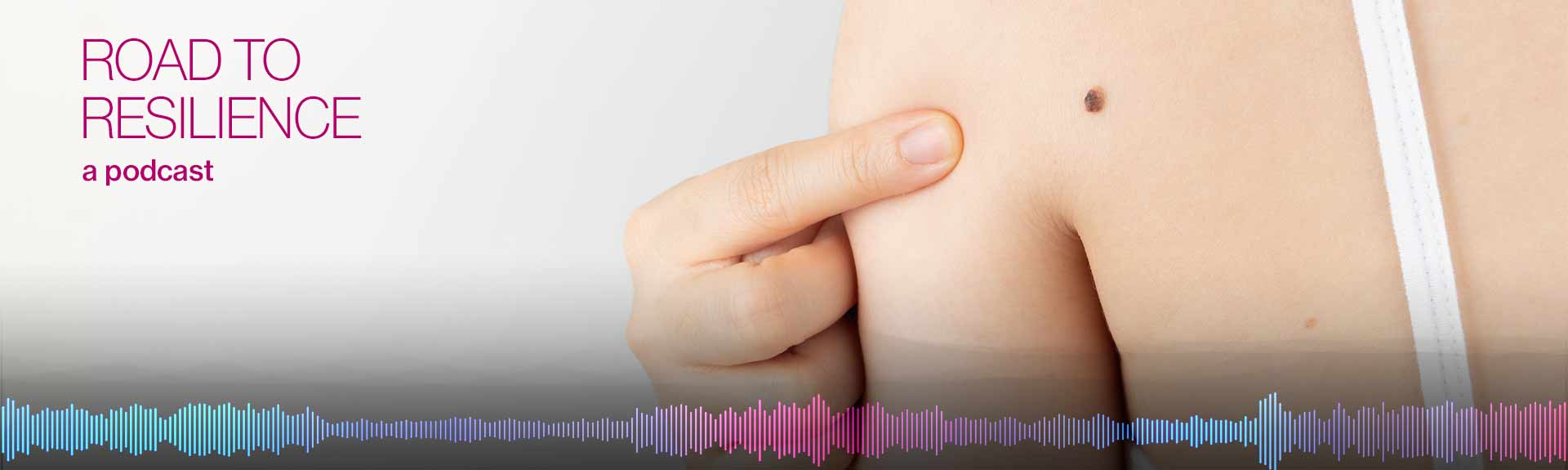 person pointing at mole on shoulder
