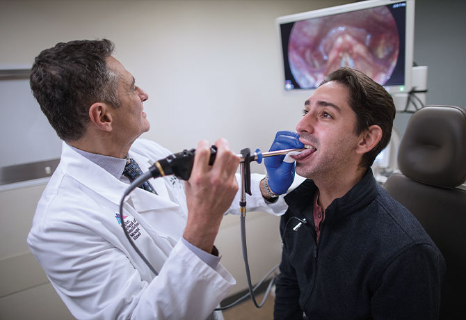 A photo of Mark S. Courey, MD, performing SEES evaluation on patient Julio Bragado-Young at The Grabscheid Voice and Swallowing Center of Mount Sinai.