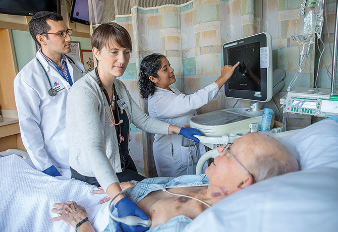 A photo of third-year residents Eric Bondarsky, MD, and Angela Love, MD, who help Paru Patrawalla, MD, perform a bedside ultrasound on Mount Sinai Beth Israel patient Paul Weidner.
