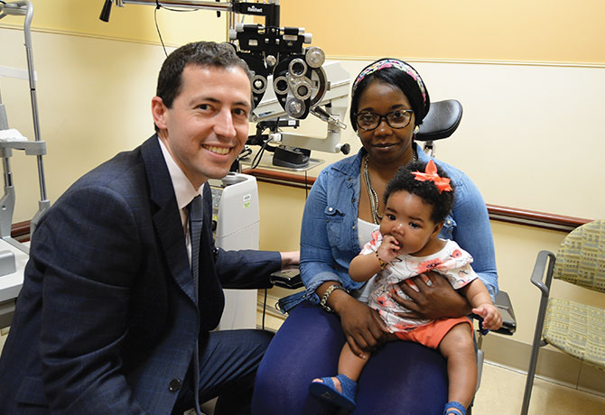 A photo showing Joseph Panarelli, MD, with four-month-old Meagan and her mother during a follow-up visit.