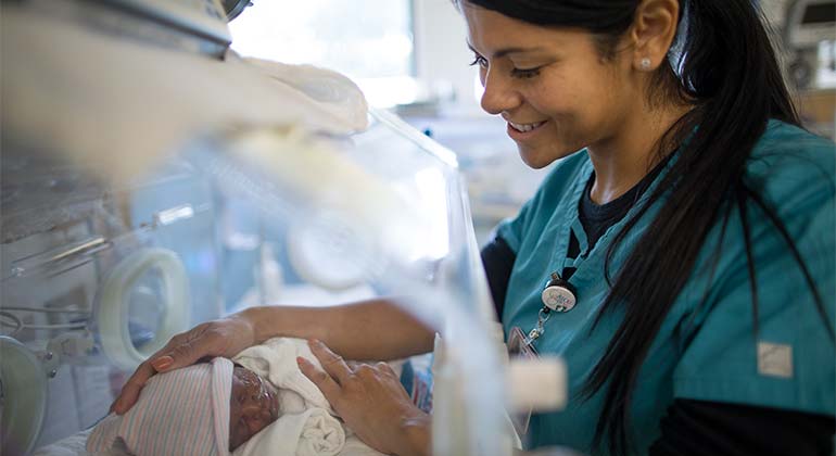 NICU doctor looking at baby in incubator