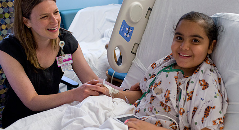 Female pediatric patient in hospital bed with social worker by her side