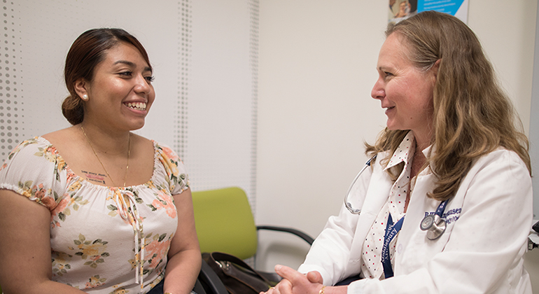 Female teenage patient sitting in chair next to female doctor