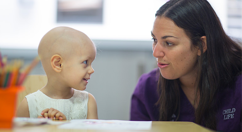 Little girl with Child Life specialist, sitting at table