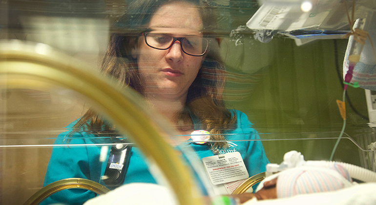 NICU doctor looking at baby in incubator