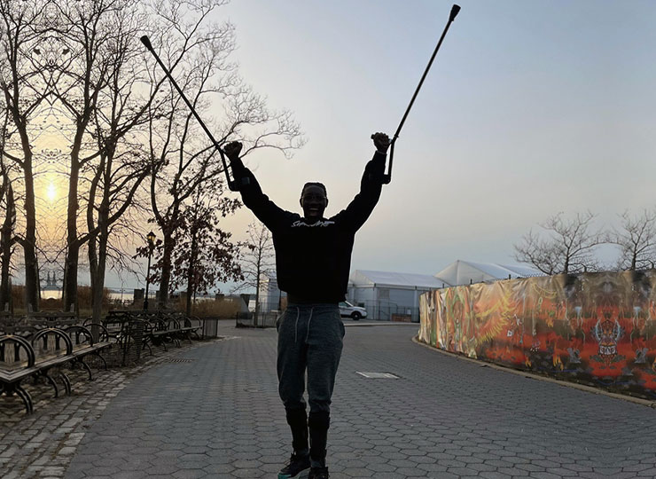 Photo of Cory Moses in park raising his crutches up in air