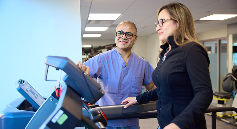 doctor helping woman walk on treadmill