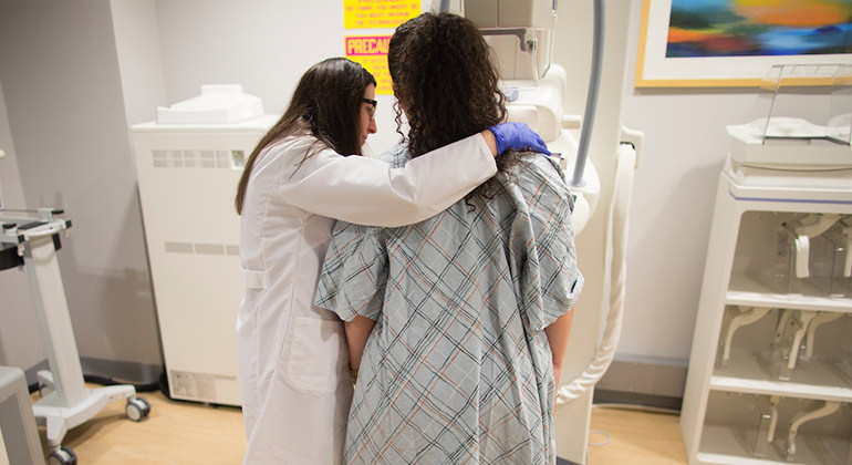 Technician performing mammogram on patient